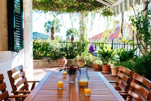 An outdoor patio with a wooden table, chairs, and potted plants.