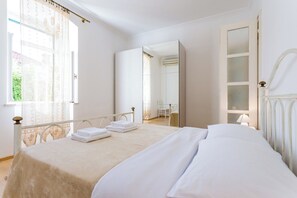 A bedroom with a bed, a chair, a desk, and a mirror.