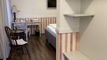 A compact room with a bed, a desk, a chair, and a TV.