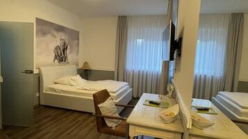 Ein Hotelzimmer mit einem Bett, einem Schreibtisch mit Stuhl, einem Fernseher und einem Bild an der Wand.