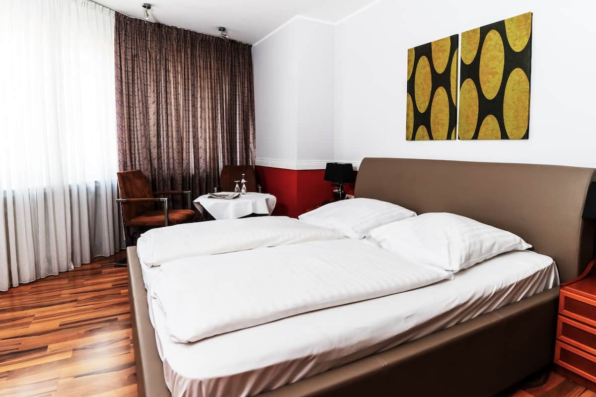 Habitación de hotel con una cama grande, un escritorio, una silla y vistas al exterior.
