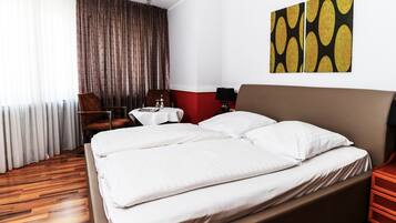 A hotel room with a large bed, a desk, a chair, and a view of the outdoors.