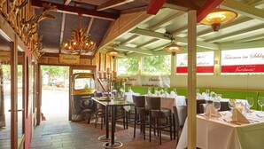 Een restaurant interieur met houten details, gedekte tafels en uitzicht op de straat.