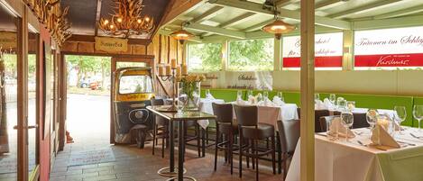 A restaurant interior with wooden decor, tables set for dining, and a view of the street outside.