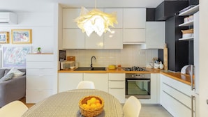 A modern kitchen with white cabinets, a central island, and a hanging light fixture. - Hedera Estate, Hedera A29 (Dubrovnik)