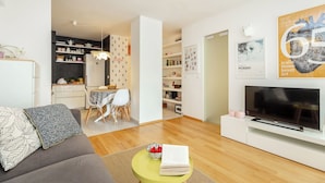 A modern living room with a sofa, a TV, a bookshelf, and a dining area. - Hedera Estate, Hedera A29 (Dubrovnik)