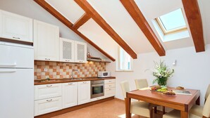 Une cuisine avec des meubles blancs, un plafond en bois et une table à manger avec des chaises.