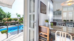 Une cuisine moderne avec une porte vitrée donnant sur un balcon et une piscine.