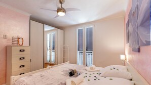 A bedroom with a bed, a wardrobe, a ceiling fan, and a window with blinds.