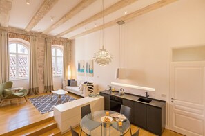 A modern apartment with a kitchen, dining area, and living room. It features exposed wooden beams, large windows, and a minimalist design.