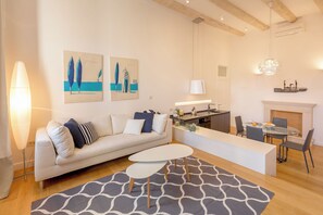 A modern living room with a sofa, a dining table, and a kitchen area.