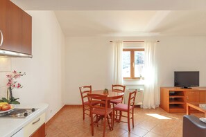 A compact living space with a dining area, kitchenette, and a TV.