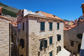 A narrow street with stone buildings, some with visible balconies and windows.