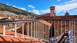 Un balcon offrant une vue sur la ville, avec ses toits en tuiles rouges et un dôme visible au loin.