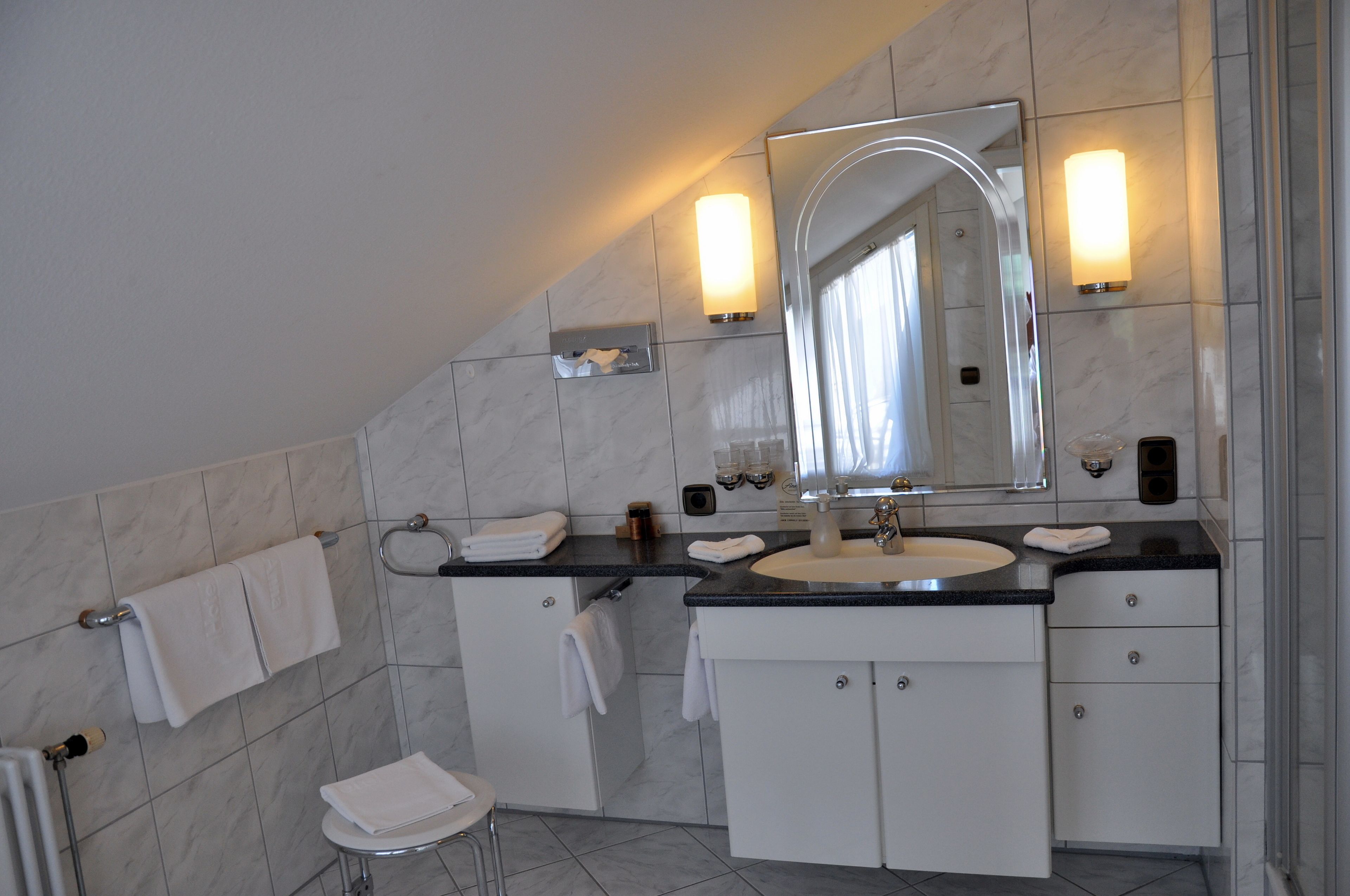 A modern bathroom with a large mirror, a sink, and a toilet.