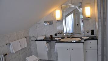 A modern bathroom with a large mirror, a sink, and a toilet.