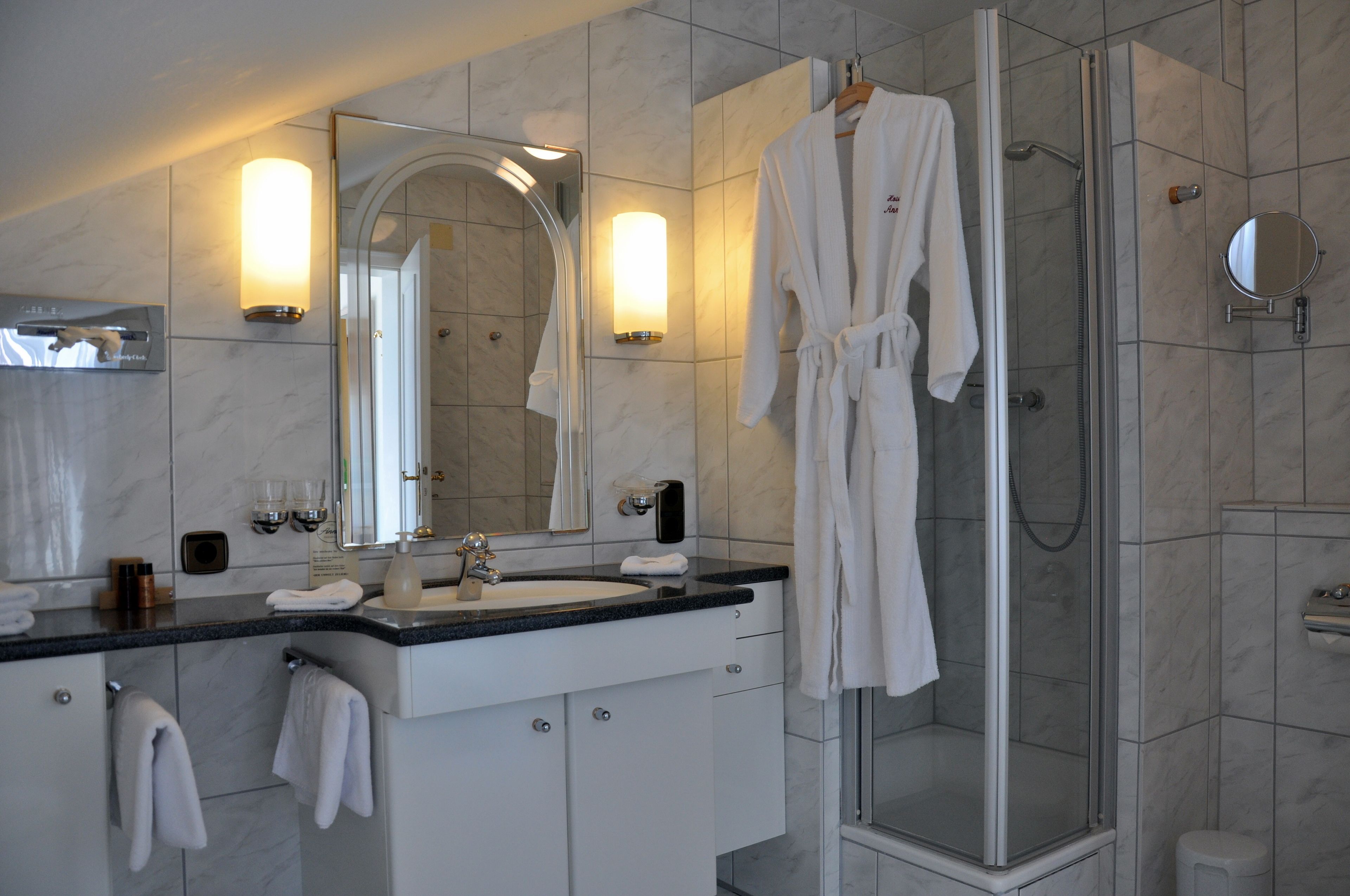 A modern bathroom with a large mirror, a sink, and a glass-enclosed shower.