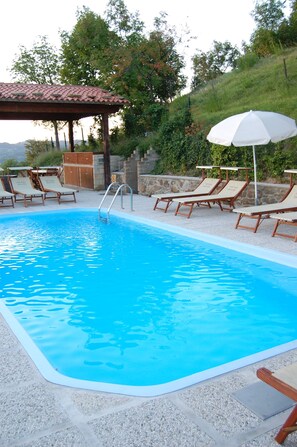 Una piscina al aire libre de temporada, sillones reclinables de piscina
