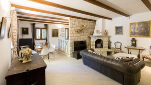 A living room with a stone fireplace, leather sofa, and wooden beams on the ceiling. - Villa Isanda - Four Bedroom Villa, Sleeps 8 (Dubrovnik)