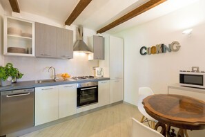 A modern kitchen with built-in appliances, a dining table, and a 'COOKING' sign. - Villa Isanda - Four Bedroom Villa, Sleeps 8 (Dubrovnik)