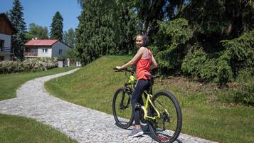 Una persona en bicicleta sobre un camino adoquinado en una zona verde y boscosa, con casas al fondo.