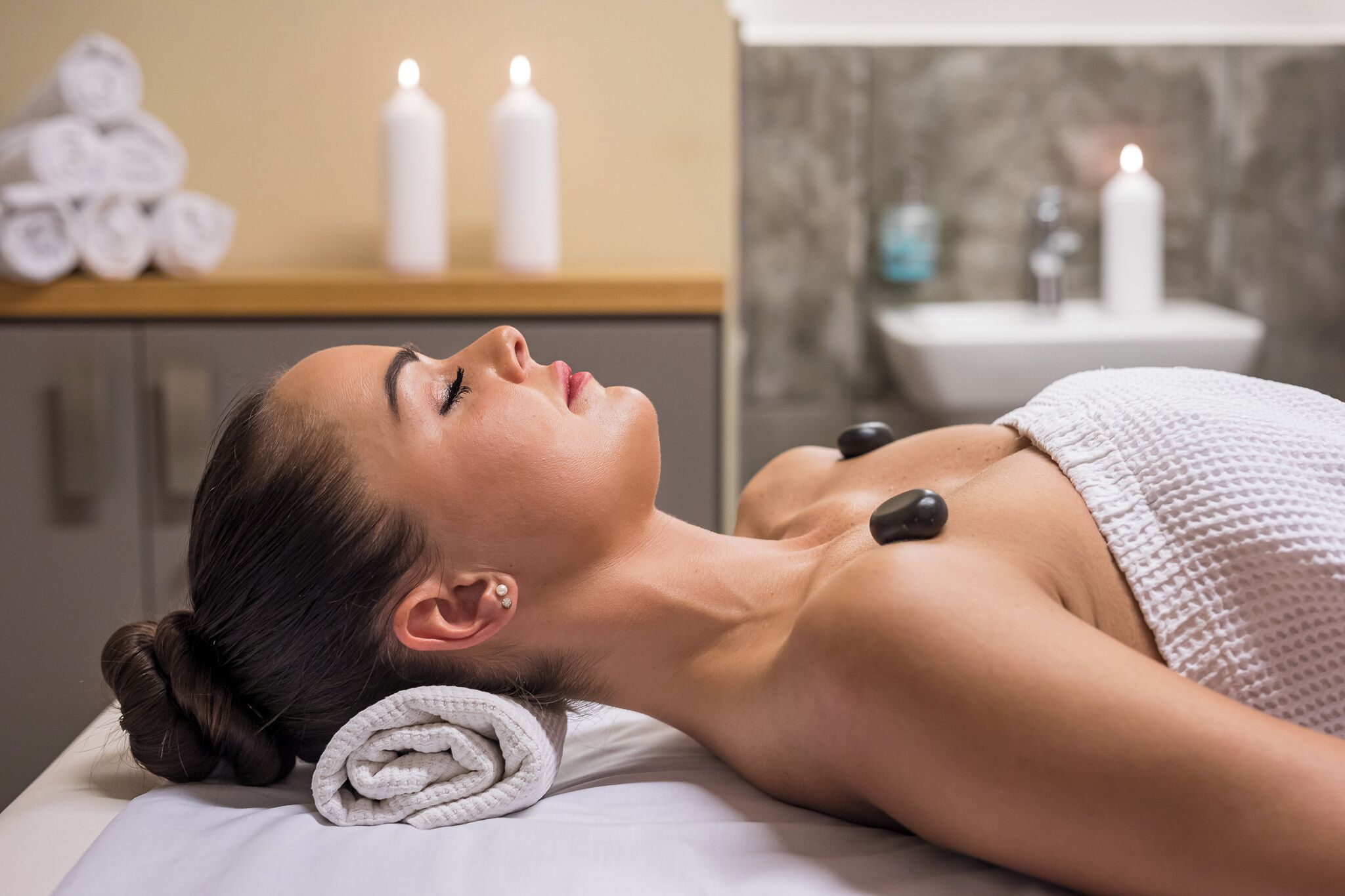 A person receiving a massage with a towel and candles in the background.