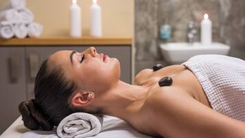 A person receiving a massage with a towel and candles in the background.