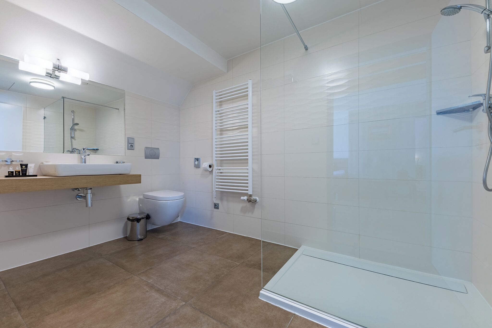 A modern bathroom with a sink, toilet, and glass shower enclosure.