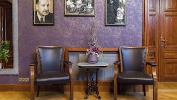 A room with two leather chairs, a small table with a vase, and three framed photographs on the wall.