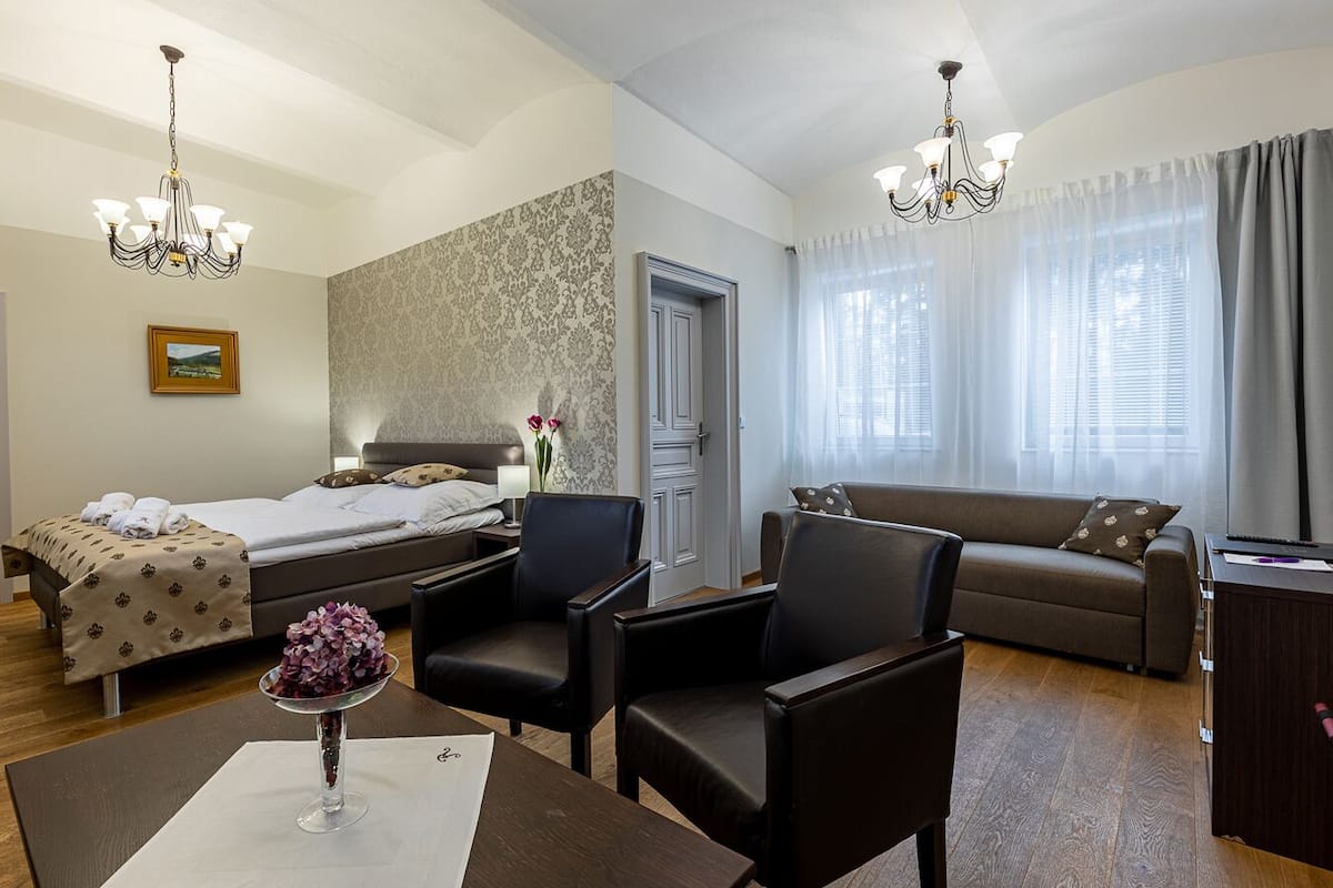 Ein Hotelzimmer mit einem Bett, zwei Sesseln, einer Couch, einem Schreibtisch und einer Chandelier.