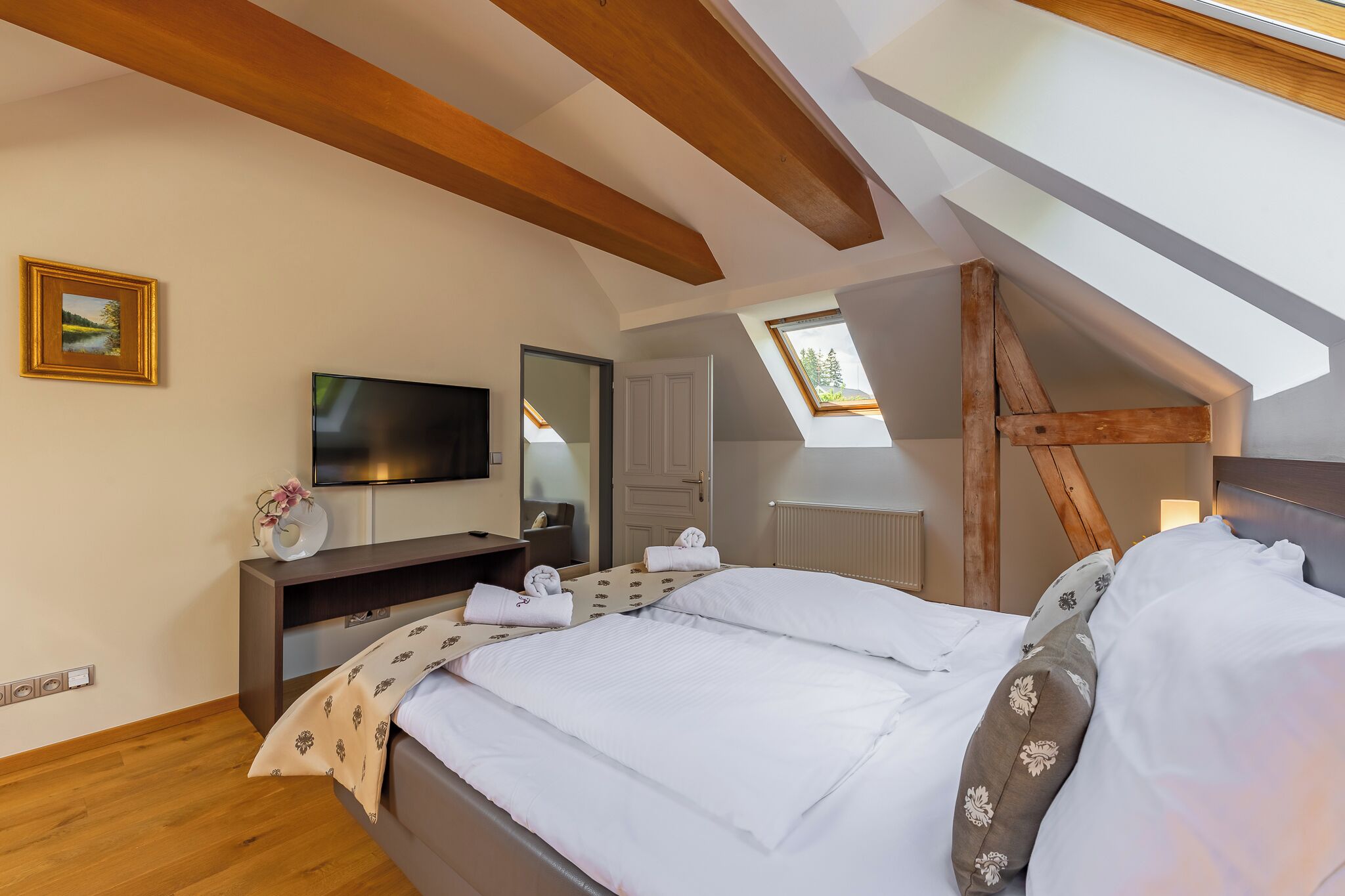 A bedroom with a bed, a TV, a desk, and a window.