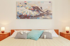 Un dormitorio con cama, dos mesitas de noche, un cuadro en la pared y una lámpara de noche.