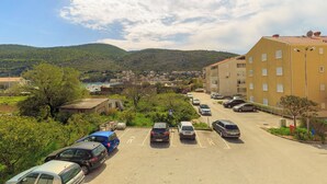 Un parking avec plusieurs voitures, un bâtiment doté de nombreuses fenêtres et un paysage montagneux en arrière-plan.