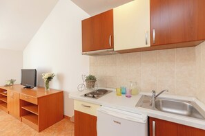 A kitchen with wooden cabinets, a white countertop, a built-in stove, a sink, and a dishwasher.