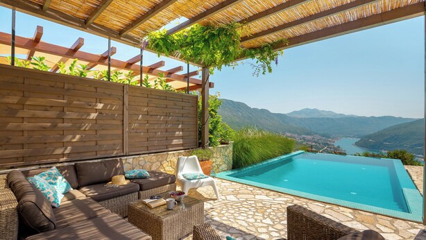 Un espace extérieur aménagé avec des sièges et une piscine, offrant une vue sur un paysage montagneux.