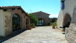 Un patio de piedra con arcos, macetas y tejado de baldosas.