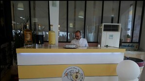 Eine Theke in einem Restaurant mit Logo, Flaschen und einer Person dahinter.