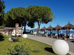 A coastal hotel with outdoor seating, a clear view of the sea, and a well-maintained garden area. - Alb. Rist. Alfredo Da Persichella (Bracciano)