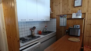 Een keuken met witte kastjes, een roestvrijstalen broodrooster en een houten aanrecht.