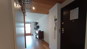 A hallway with a wooden floor, a black door with a notice, and a desk with a computer and shelves. - Comfortable apartment in Montgenèvre with balcony and parking (Montgenèvre)