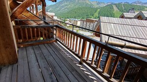 A wooden balcony with a view of a mountainous landscape and buildings in the background. - Comfortable apartment in Montgenèvre with balcony and parking (Montgenèvre)