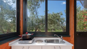 Una cucina con fornello, lavandino e finestra con vista su un giardino.