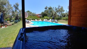 Una vasca idromassaggio con vista su una piscina e un'area salotto all'aperto.