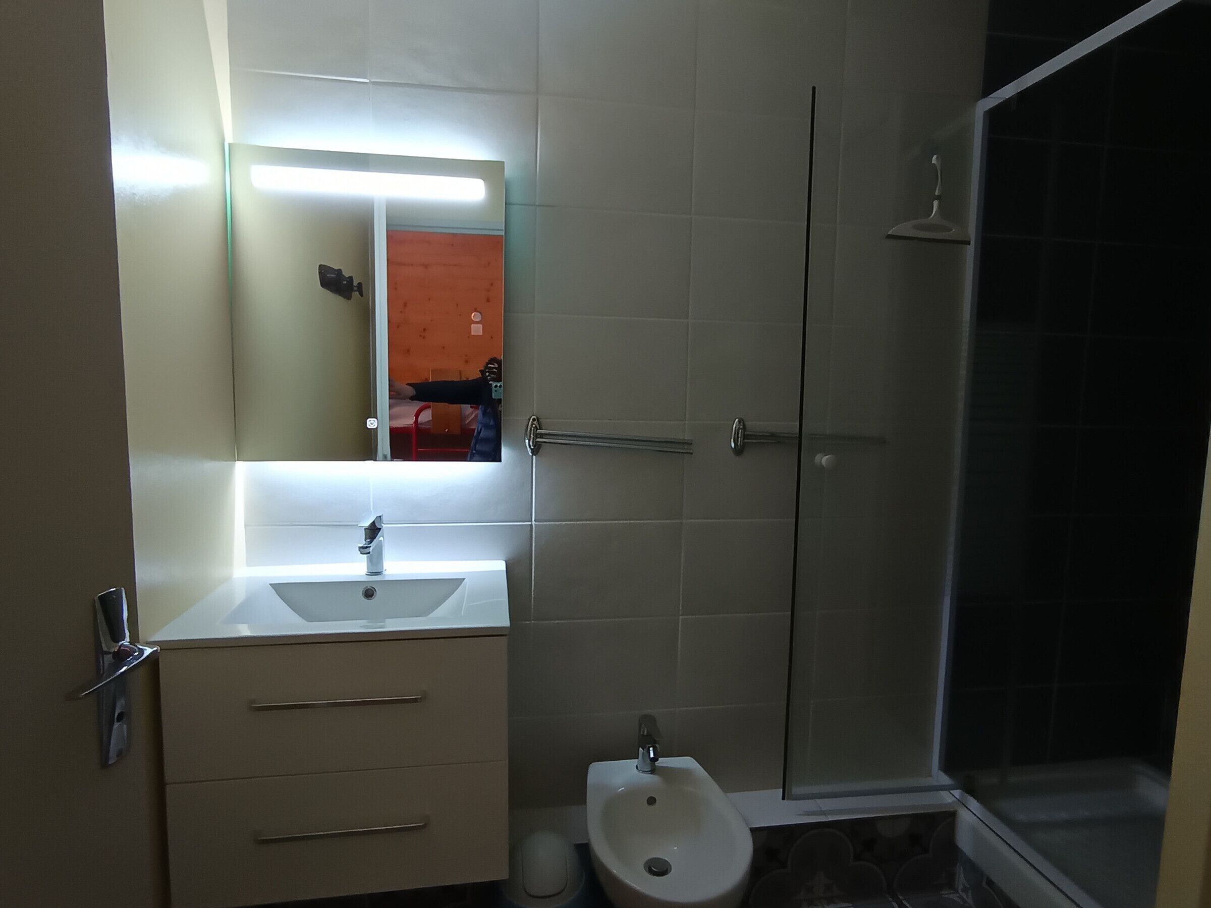 A bathroom with a sink, mirror, and a shower.