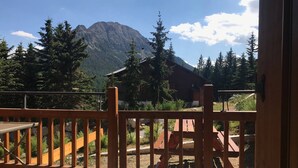 A wooden deck with a view of a mountain and a building in the background. - Lovely apartment 6 people, terrace, garage, pets welcome (Montgenèvre)