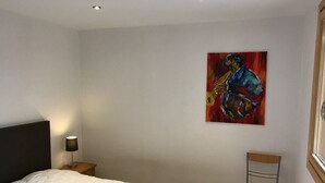 A bedroom with a bed, a chair, a nightstand, a lamp, and a painting on the wall. - Lovely apartment 6 people, terrace, garage, pets welcome (Montgenèvre)