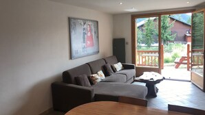 A living room with a sofa, a coffee table, and a painting on the wall. - Lovely apartment 6 people, terrace, garage, pets welcome (Montgenèvre)