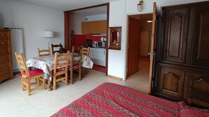 A compact living space with a dining area, kitchen, and a large wardrobe.