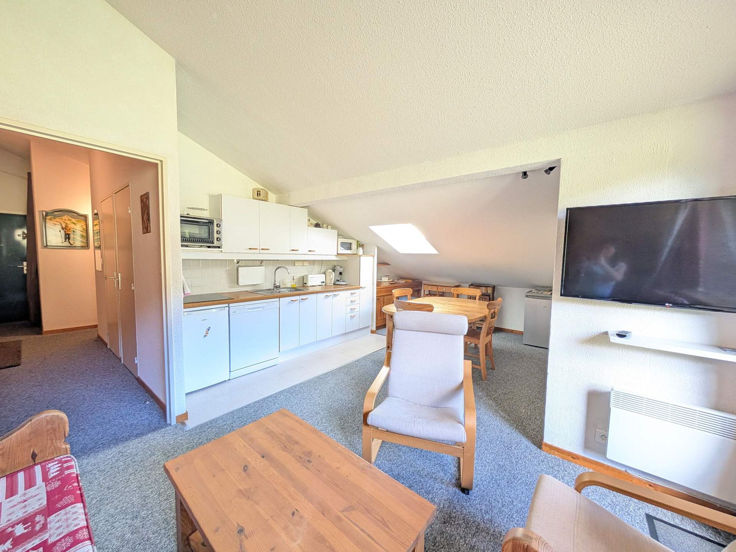 Un espace de vie compact comprenant un coin cuisine, un espace repas et un téléviseur.