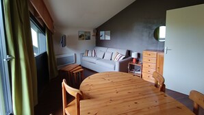 A cozy living room with a wooden dining table, a sofa, and a small side table. - Lovely 2P 5 Pers Ski-in Ski-out Top Floor Pets Welcome (Montgenèvre)